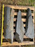 Three hand-split dark slate slabs on a pallet with tape measure