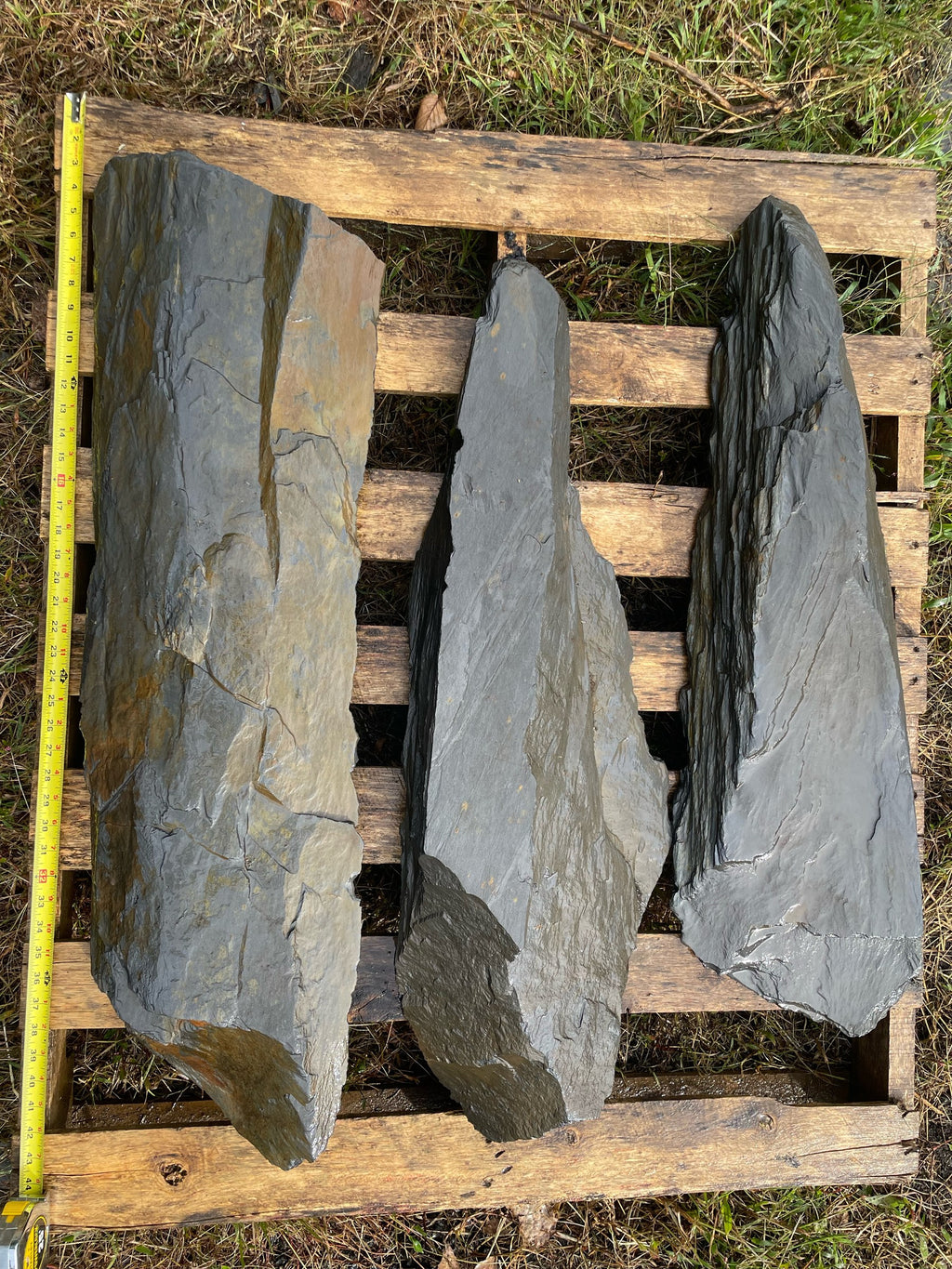 Hand-split charcoal slate slabs with natural rough edges on a pallet