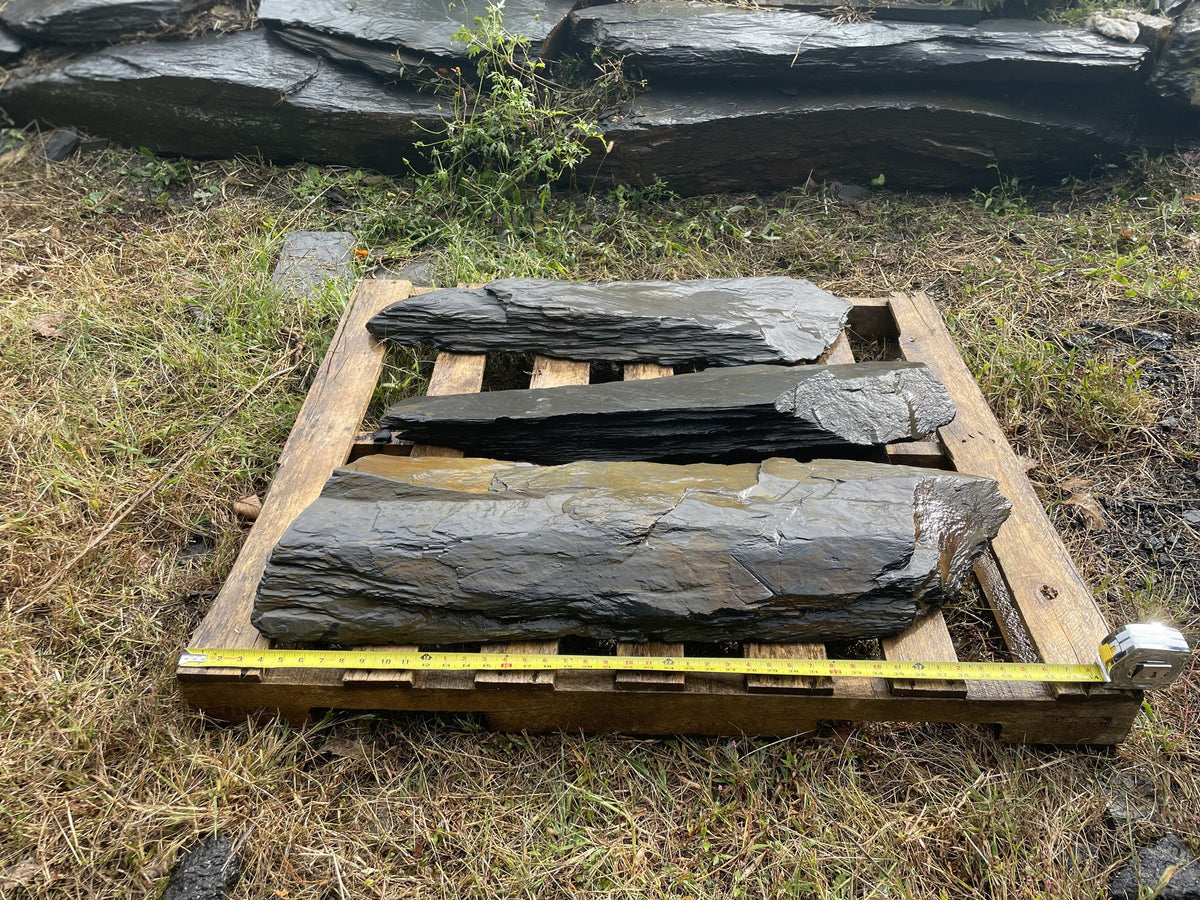 Three dark slate slabs on a pallet ready for freight shipping