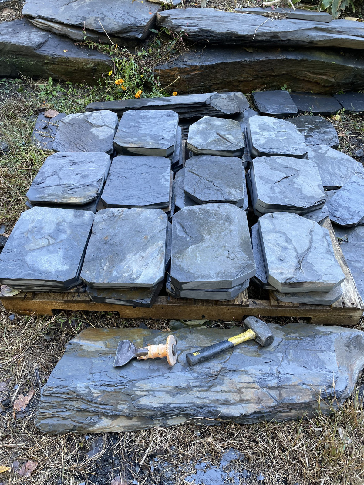 Hand-split Maryland Peach Bottom slate steppingstones stacked on a pallet with hammer and chisel