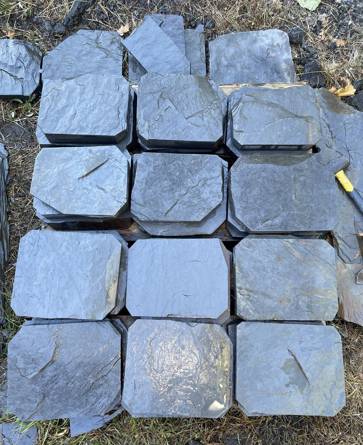 Overhead view of hand-split slate steppingstones with clipped corners laid out on a pallet
